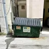Waste Management [WM] - Small waste Dumpster behind a commercial building
